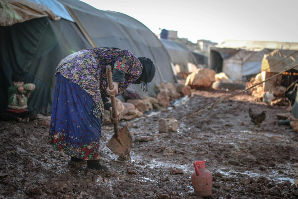 pexels-photo-10629463-10629463 An elderly woman works in the mud at an outdoor refugee camp in Idlib, Syria.