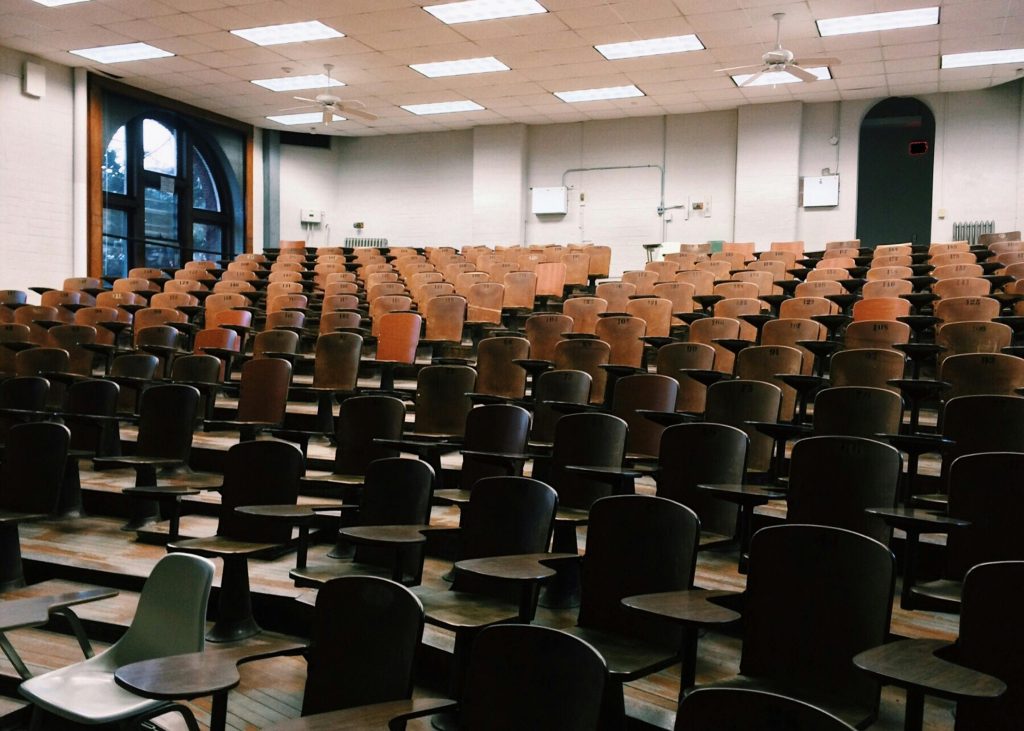 pexels-photo-356065-356065 Empty university lecture hall with wooden chairs and large windows.