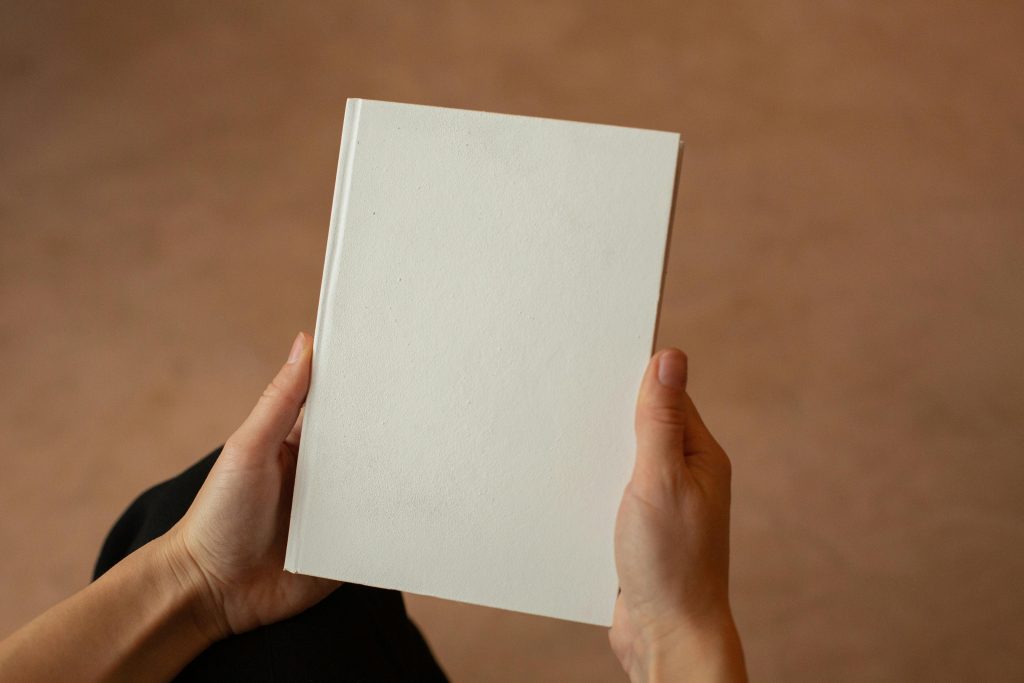 A person holding a blank hardcover book. Perfect for mockup and design templates.